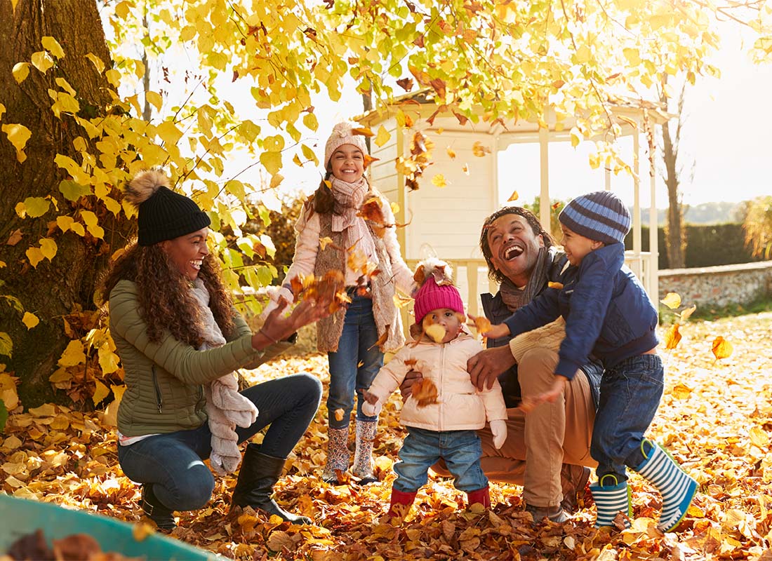 Read Our Reviews - Portrait of a Cheerful Family with Three Kids Having Fun Playing with the Falling Leaves in Their Backyard During the Fall